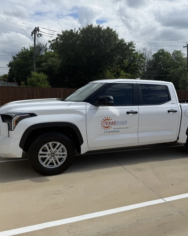 A white Texas Shade work truck with the Texas Shade logo and "Serving DFW since 2012" on the door, parked in a lot