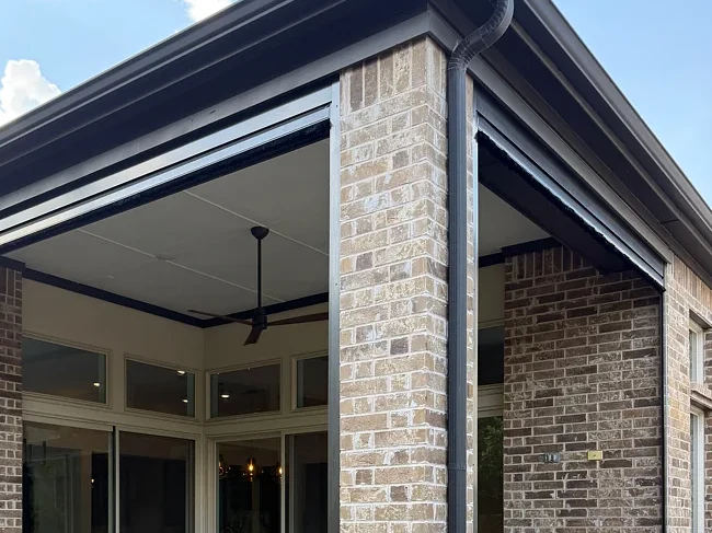 Brick home's covered patio with the shades raised into visible headers above the opening